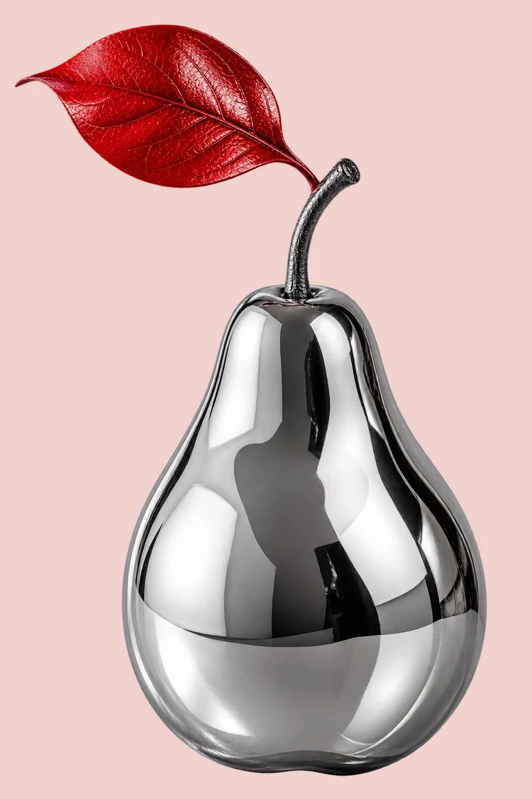 A mirror-bright chrome pear carries a vivid red leaf against soft pink.